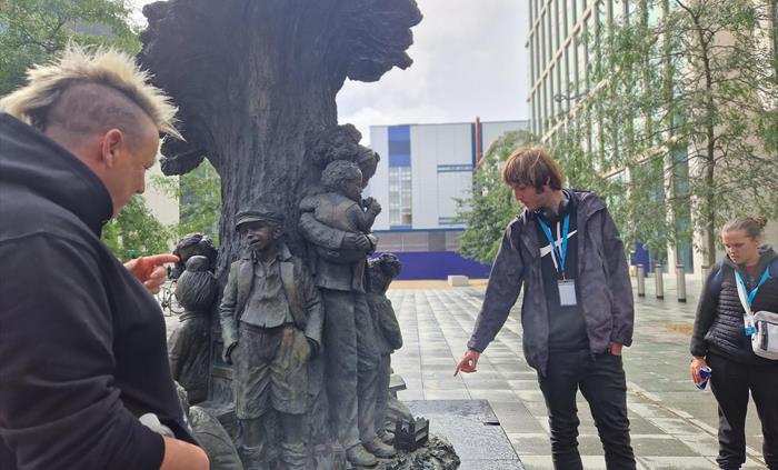 Tour guide pointing at Betty Cambell statue